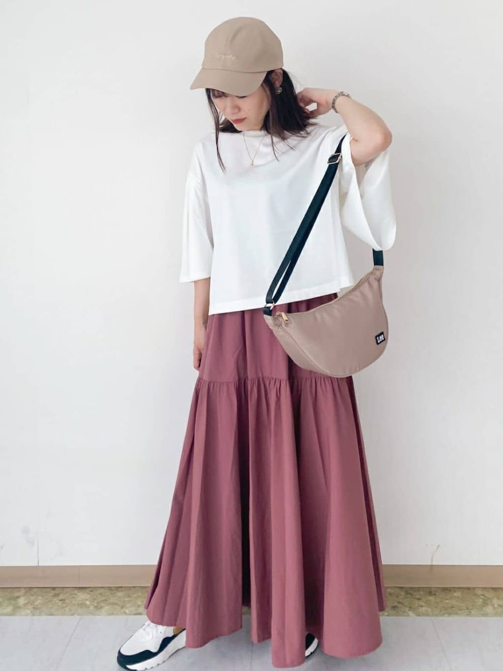 ピンク系のスカート、ホワイト系のTシャツ/カットソー、ベージュ系のショルダーバッグを着用したレディースの秋コーディネートの1枚目の写真