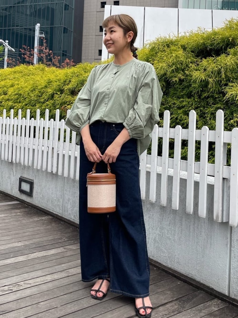 グリーン系のシャツ/ブラウス、ブルー系のデニムパンツ、ブラウン系のショルダーバッグを着用したレディースの春コーディネートの1枚目の写真