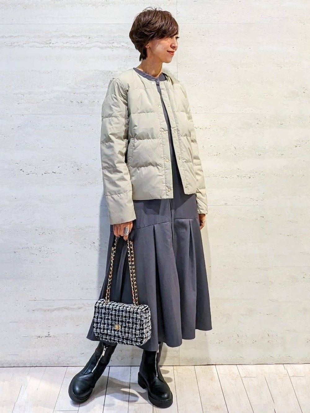 グリーン系のダウンジャケット/コート、グレー系のワンピース、ブラック系のショルダーバッグを着用したレディースの秋コーディネートの1枚目の写真