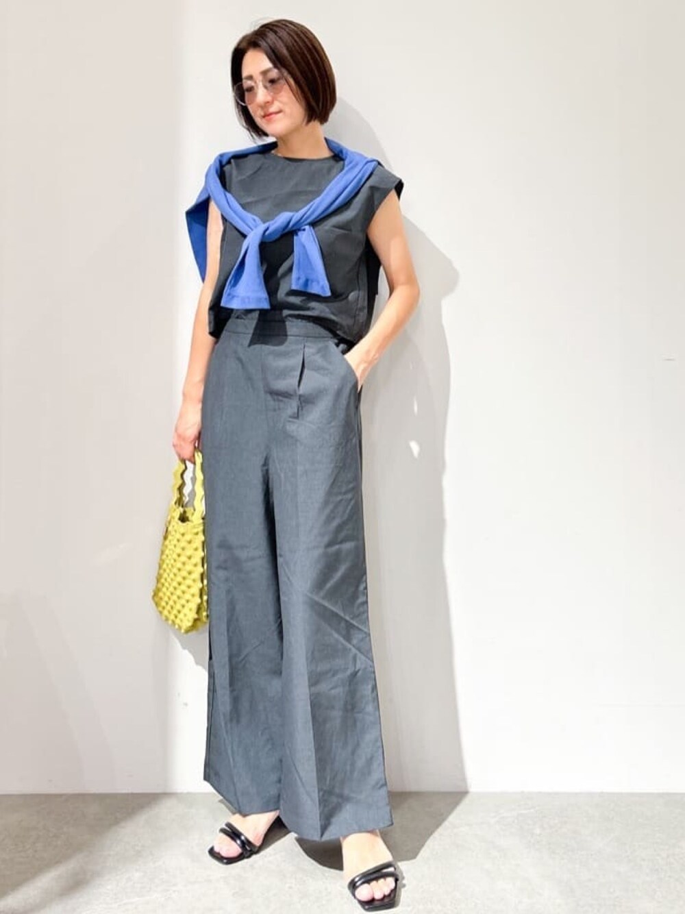 グレー系のサロペット/オーバーオール、ブルー系のカーディガン/ボレロ、イエロー系のハンドバッグを着用したレディースの夏コーディネートの1枚目の写真