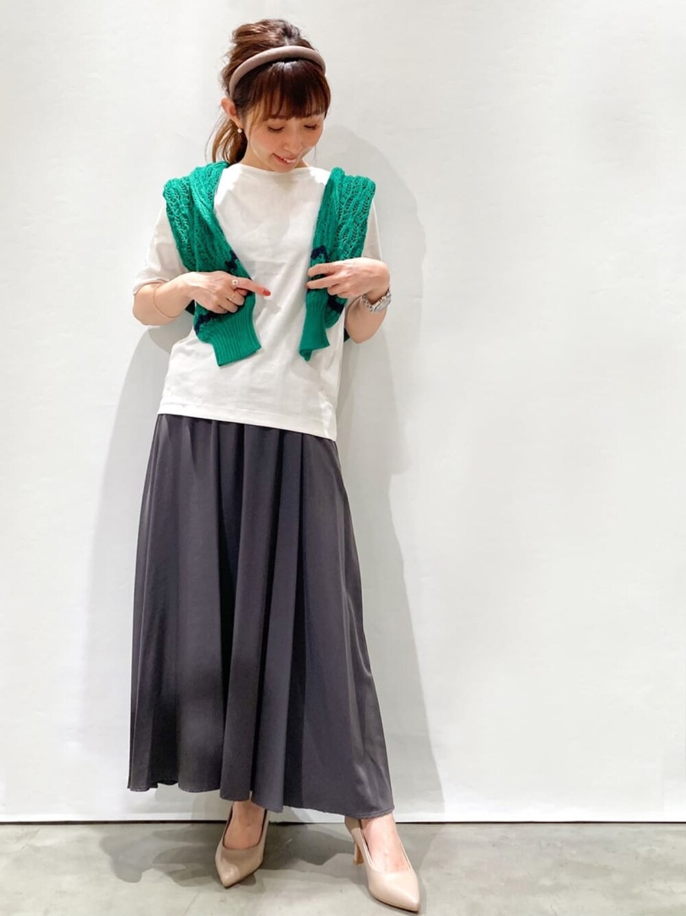 グレー系のスカート、ホワイト系のTシャツ/カットソー、グリーン系のカーディガン/ボレロを着用したレディースの夏コーディネートの1枚目の写真