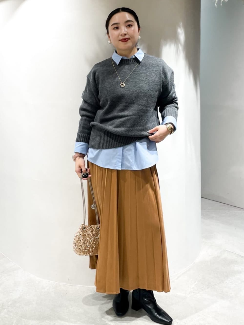 イエロー系のスカート、ブラック系のブーツ、ブルー系のシャツ/ブラウスを着用したレディースの秋コーディネートの1枚目の写真