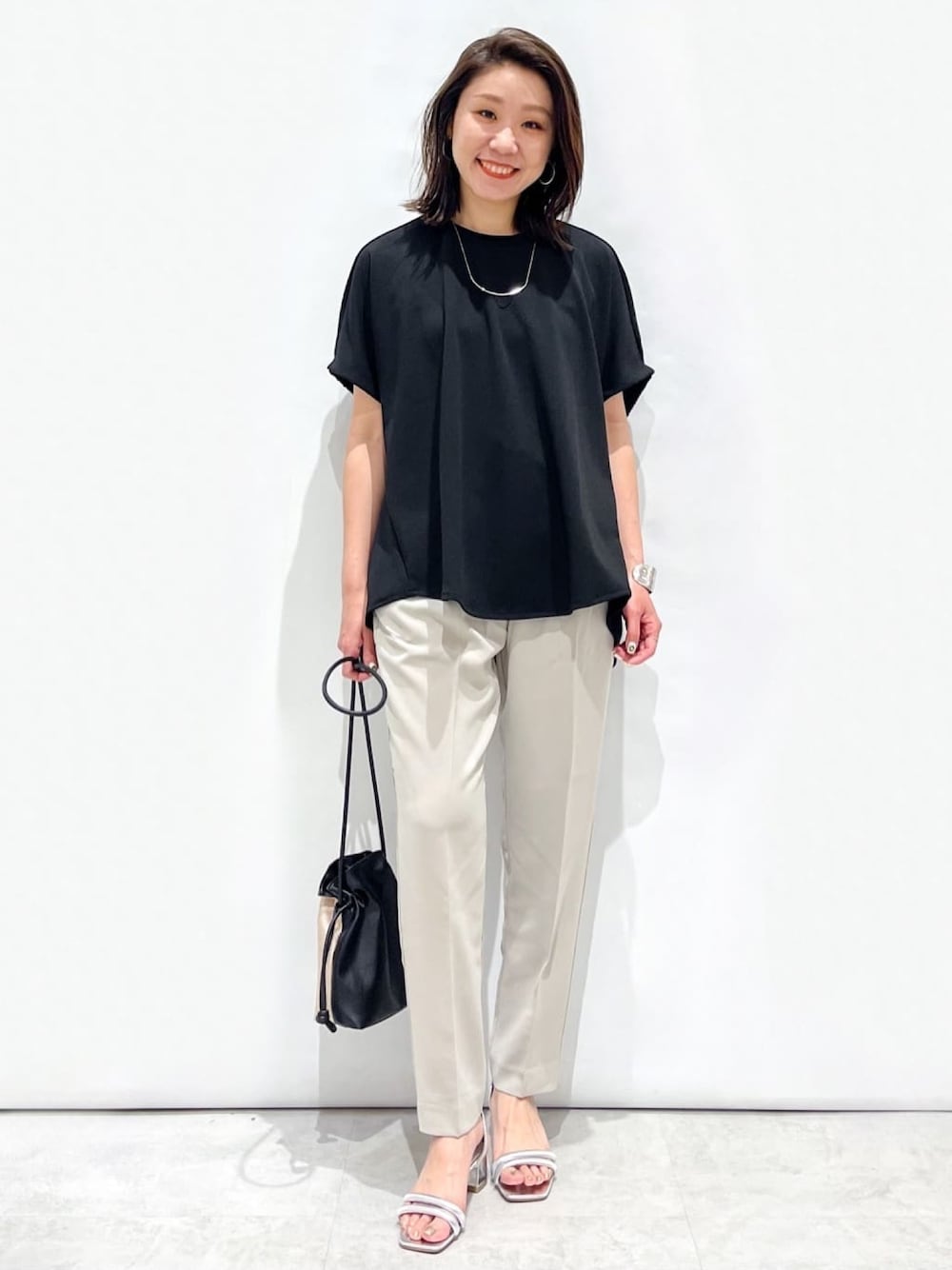 ブラック系のTシャツ/カットソー、グレー系のその他パンツ、シルバー系のサンダルを着用したレディースの春コーディネートの1枚目の写真