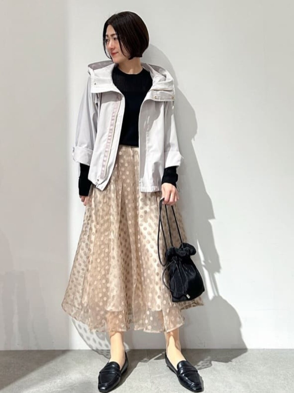 ベージュ系のブルゾン、ブラック系のニット/セーター、ベージュ系のスカートを着用したレディースの春コーディネートの1枚目の写真