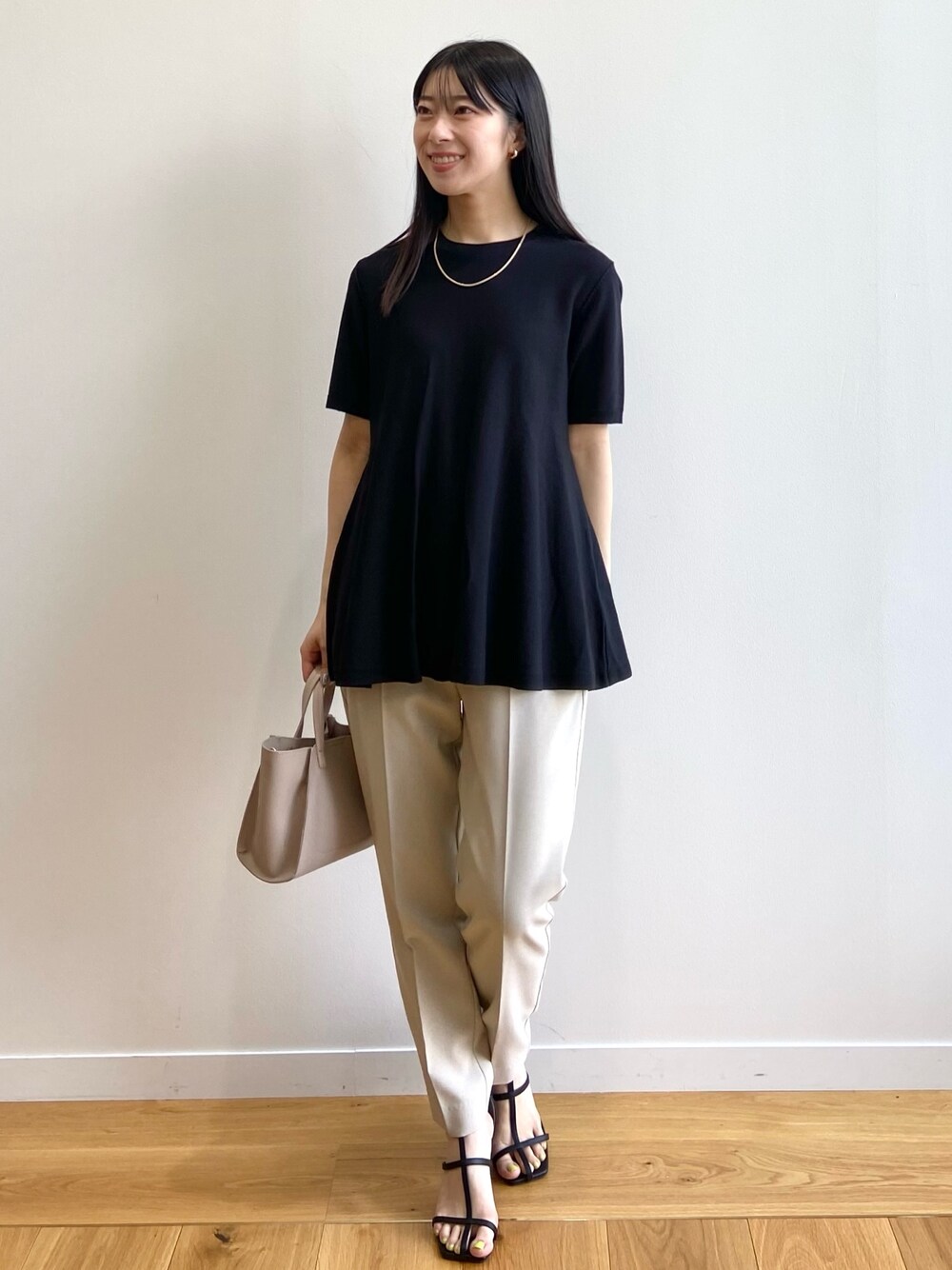 ブラック系のニット/セーター、ベージュ系のその他パンツ、ベージュ系のトートバッグを着用したレディースの春コーディネートの1枚目の写真