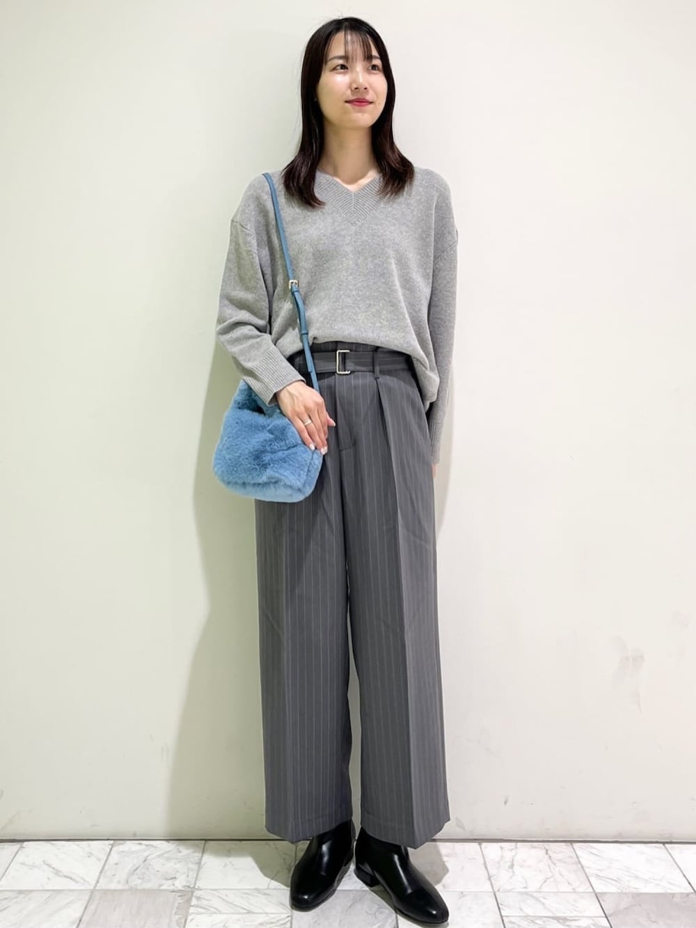 グレー系のニット/セーター、グレー系のその他パンツ、ブルー系のショルダーバッグを着用したレディースの冬コーディネートの1枚目の写真