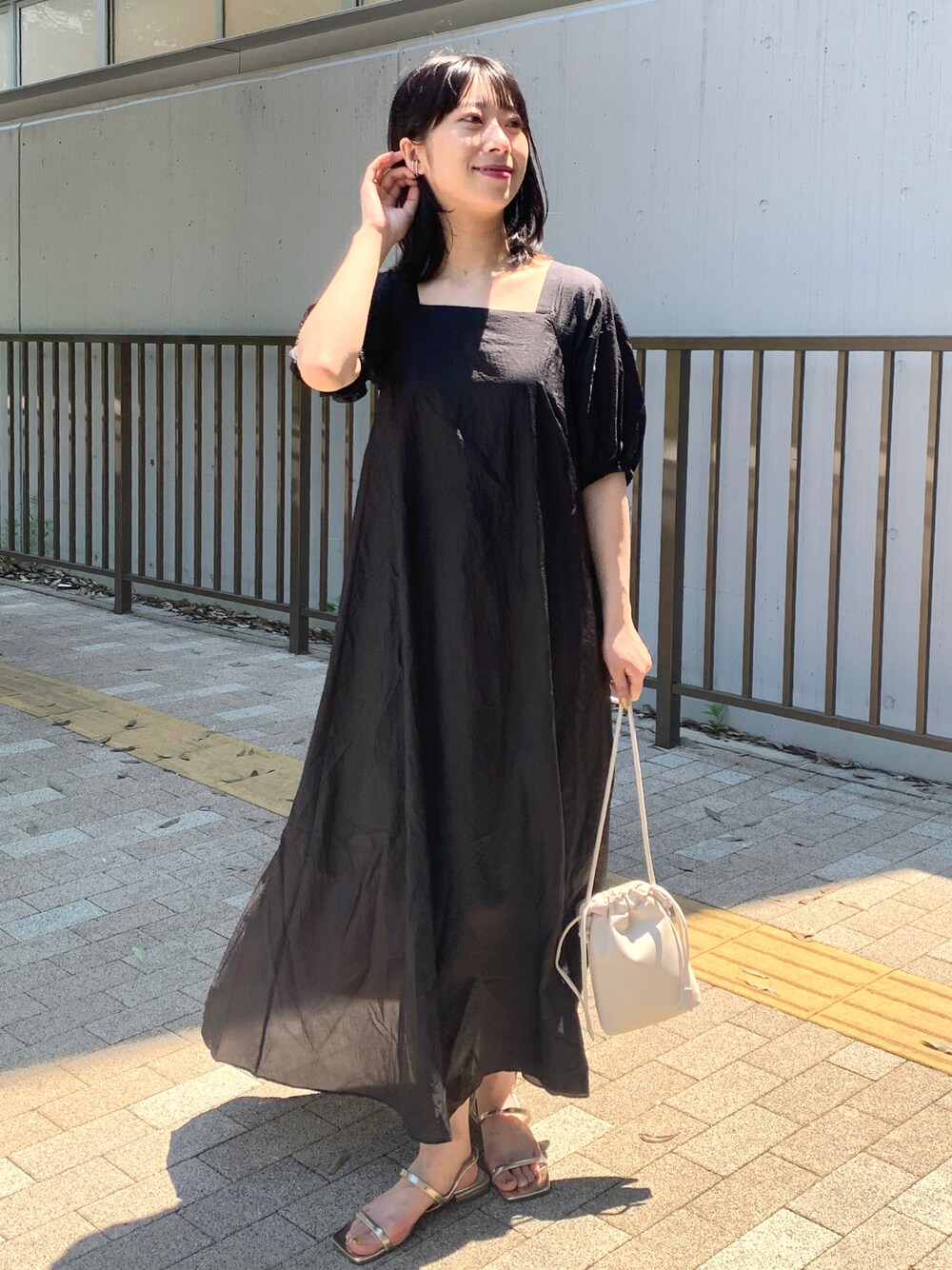 ブラック系のワンピース、ホワイト系のショルダーバッグ、ゴールド系のサンダルを着用したレディースの夏コーディネートの1枚目の写真