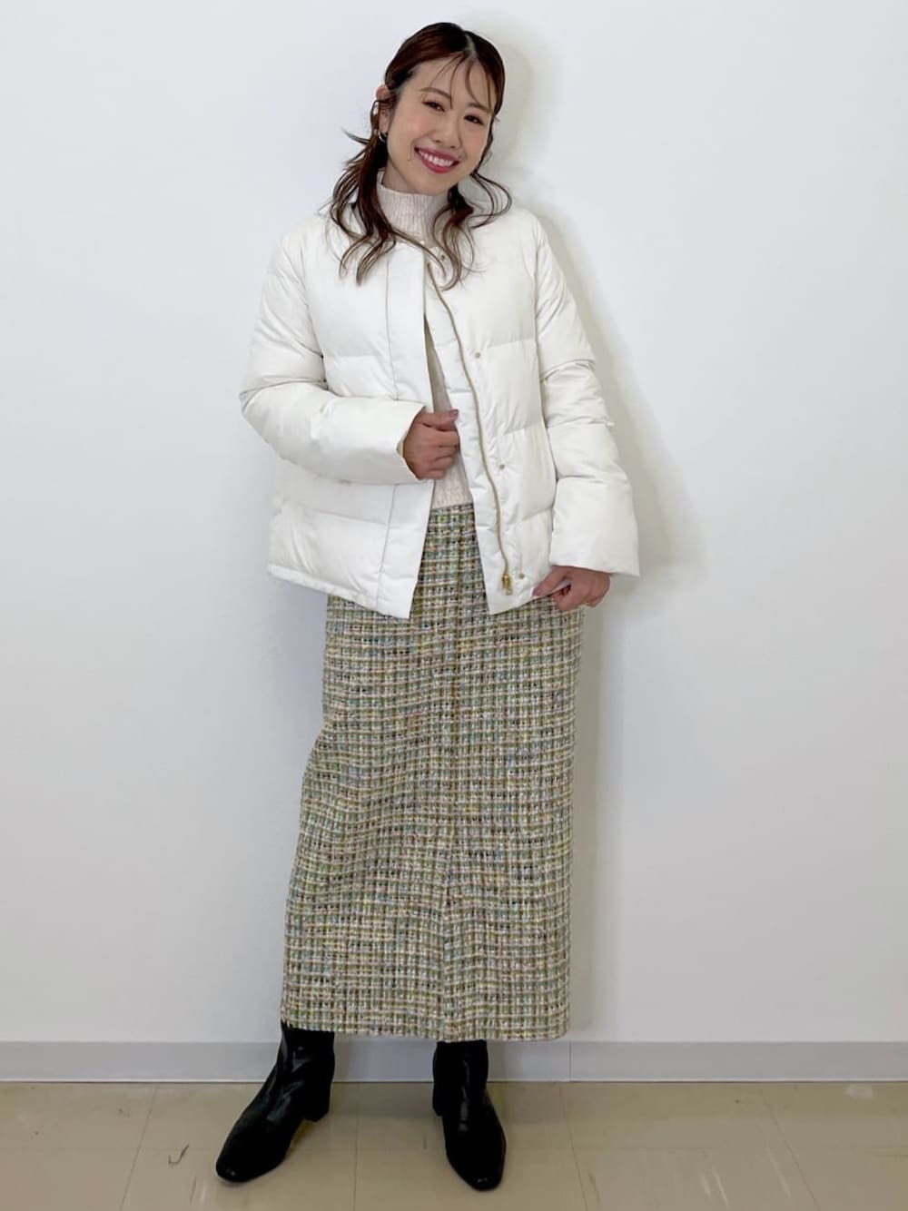 グリーン系のスカート、ホワイト系のダウンジャケット/コート、ホワイト系のニット/セーターを着用したレディースの冬コーディネートの1枚目の写真