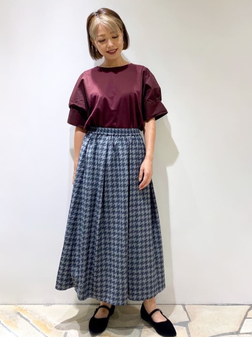 レッド系のTシャツ/カットソー、グレー系のスカート、ブラック系のパンプスを着用したレディースの秋コーディネートの1枚目の写真