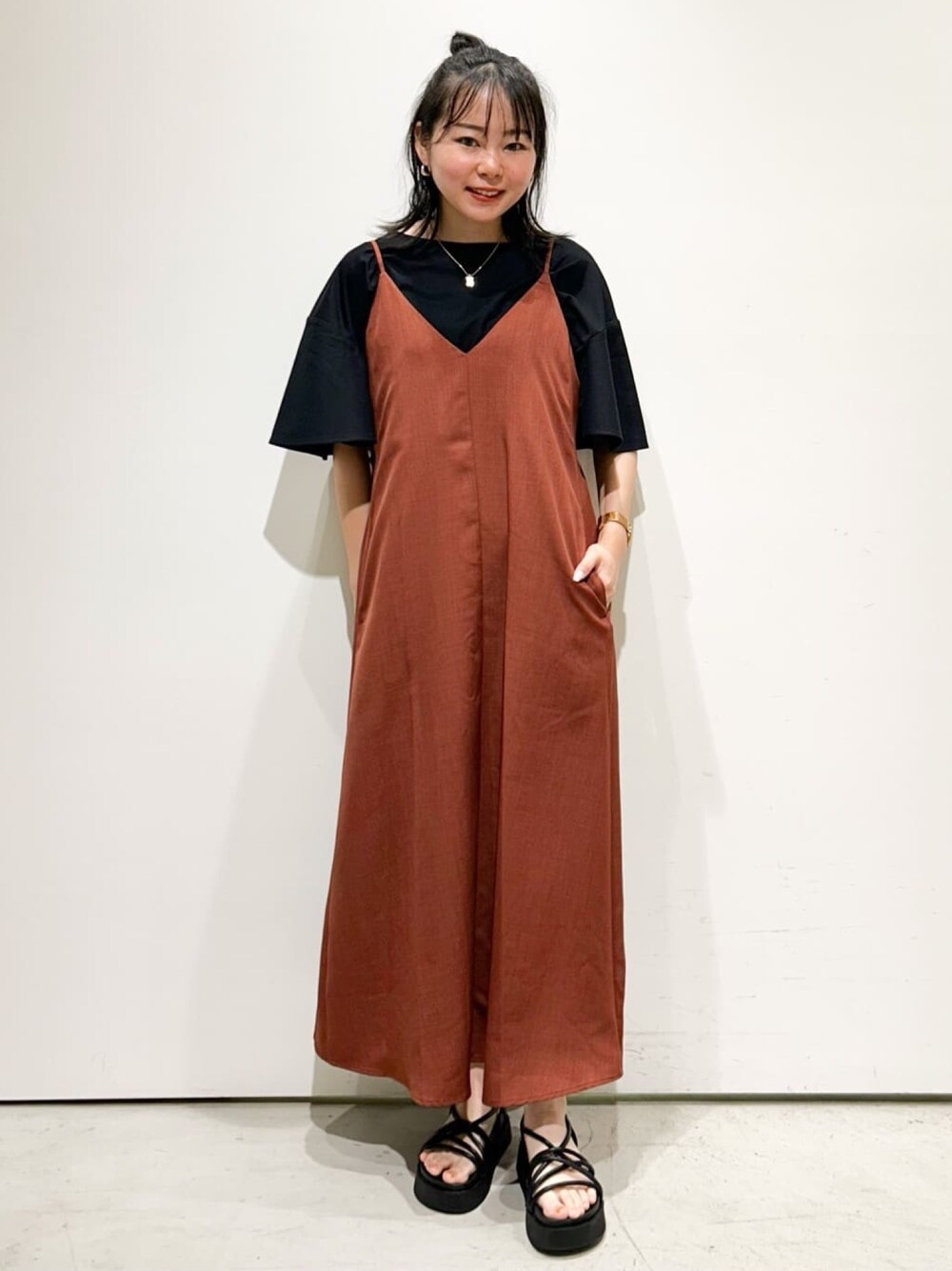 オレンジ系のワンピース、ブラック系のTシャツ/カットソー、ブラック系のサンダルを着用したレディースの夏コーディネートの1枚目の写真