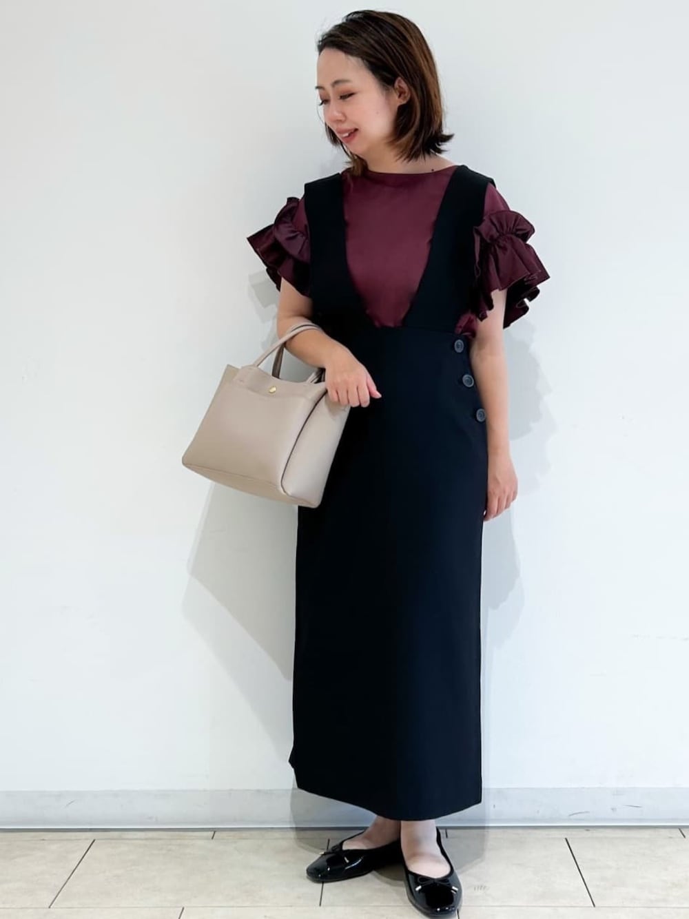レッド系のTシャツ/カットソー、ベージュ系のトートバッグ、ブラック系のスカートを着用したレディースの夏コーディネートの1枚目の写真