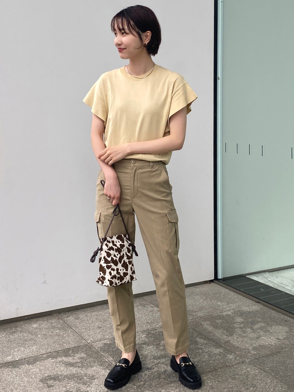 ベージュ系のその他パンツ、ブラウン系のショルダーバッグ、イエロー系のニット/セーターを着用したレディースの夏コーディネートの1枚目の写真