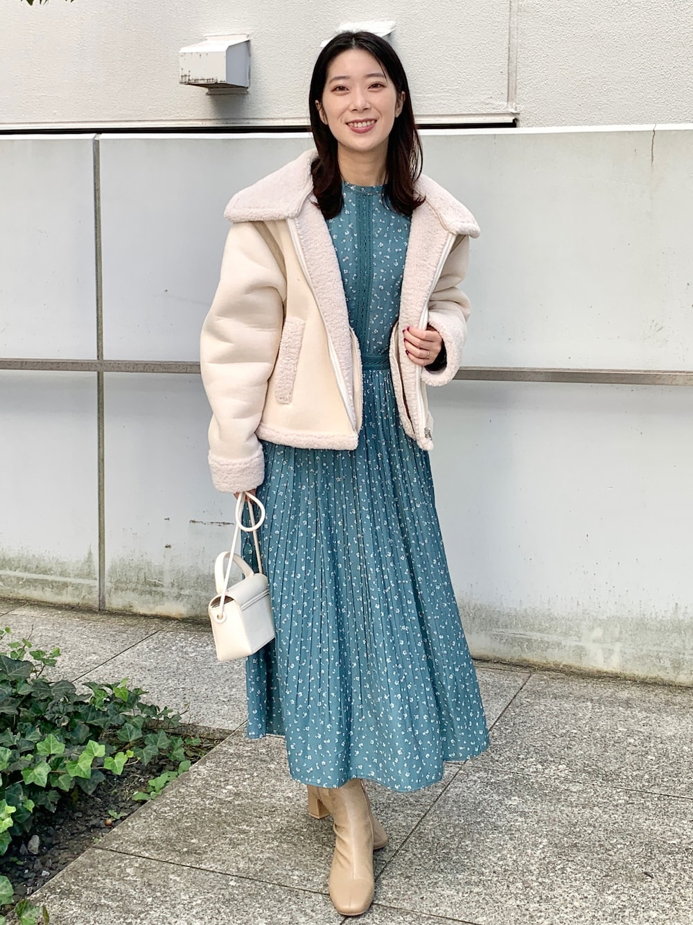 ベージュ系のブルゾン、ブルー系のワンピース、ホワイト系のショルダーバッグを着用したレディースの秋コーディネートの1枚目の写真