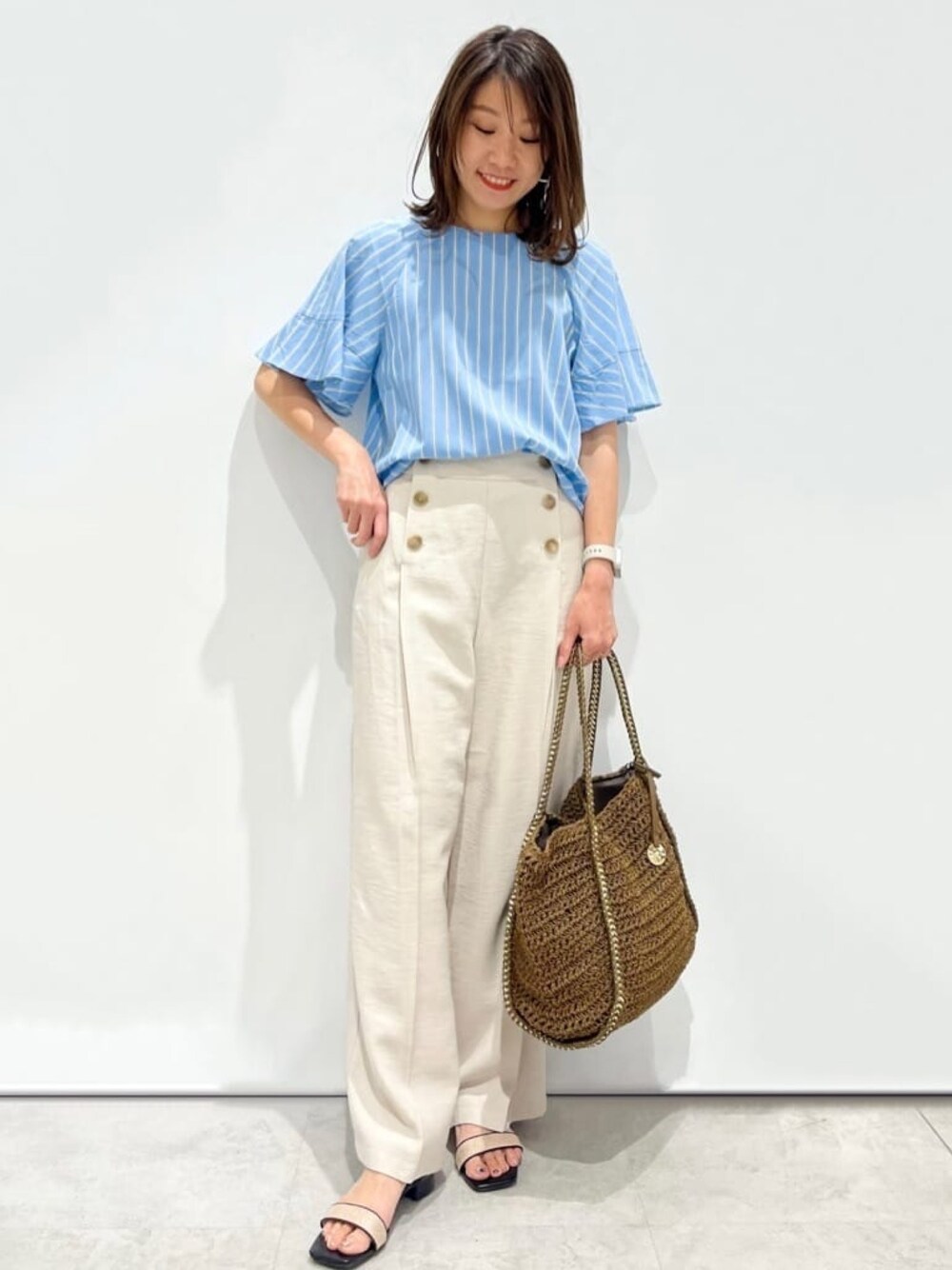 ブルー系のシャツ/ブラウス、ベージュ系のその他パンツ、ブラウン系のトートバッグを着用したレディースの春コーディネートの1枚目の写真