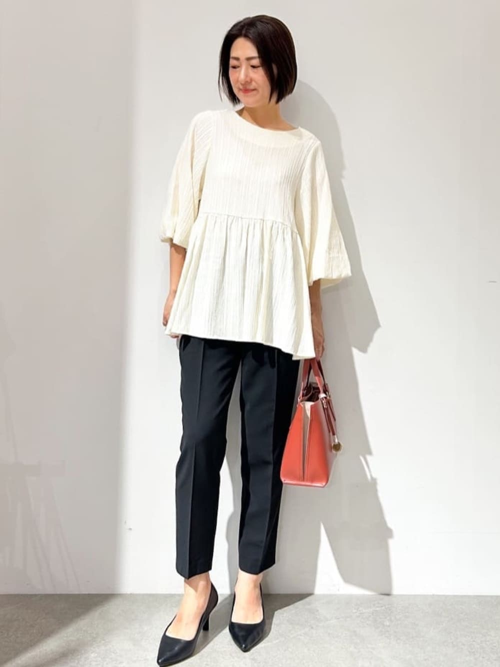 ホワイト系のシャツ/ブラウス、ブラック系のパンプス、レッド系のトートバッグを着用したレディースの夏コーディネートの1枚目の写真