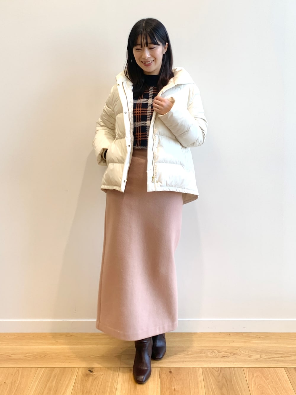ホワイト系のダウンジャケット/コート、ブルー系のニット/セーター、ブラウン系のブーツを着用したレディースの冬コーディネートの1枚目の写真