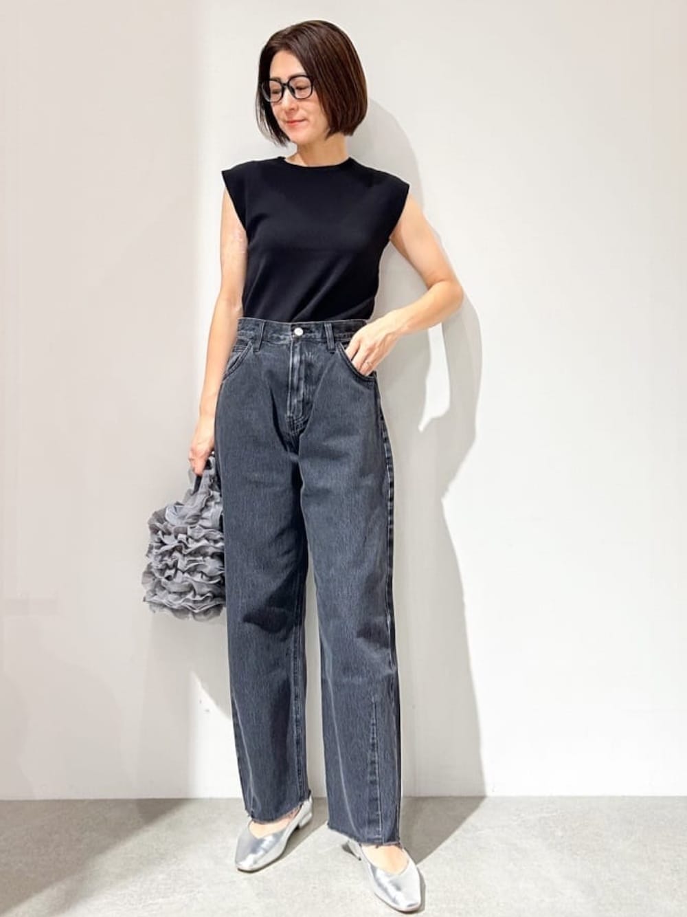 ブラック系のニット/セーター、グレー系のデニムパンツ、シルバー系のパンプスを着用したレディースの夏コーディネートの1枚目の写真