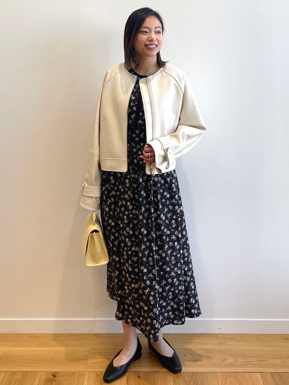 ベージュ系のノーカラージャケット、ブラック系のワンピース、イエロー系のショルダーバッグを着用したレディースの春コーディネートの1枚目の写真