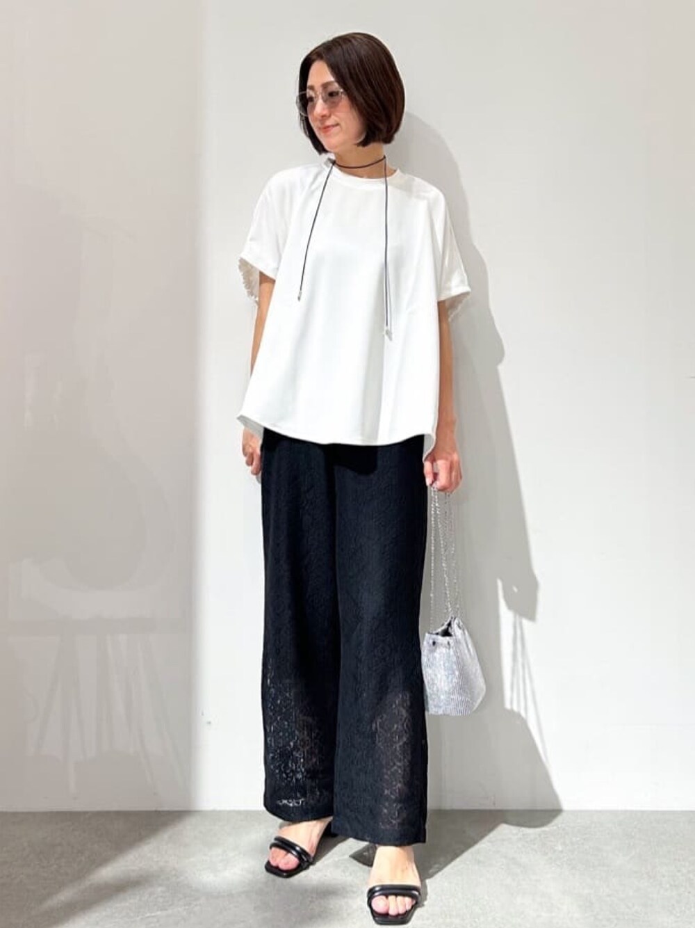 ホワイト系のTシャツ/カットソー、ブラック系のその他パンツ、ブラック系のサンダルを着用したレディースの春コーディネートの1枚目の写真