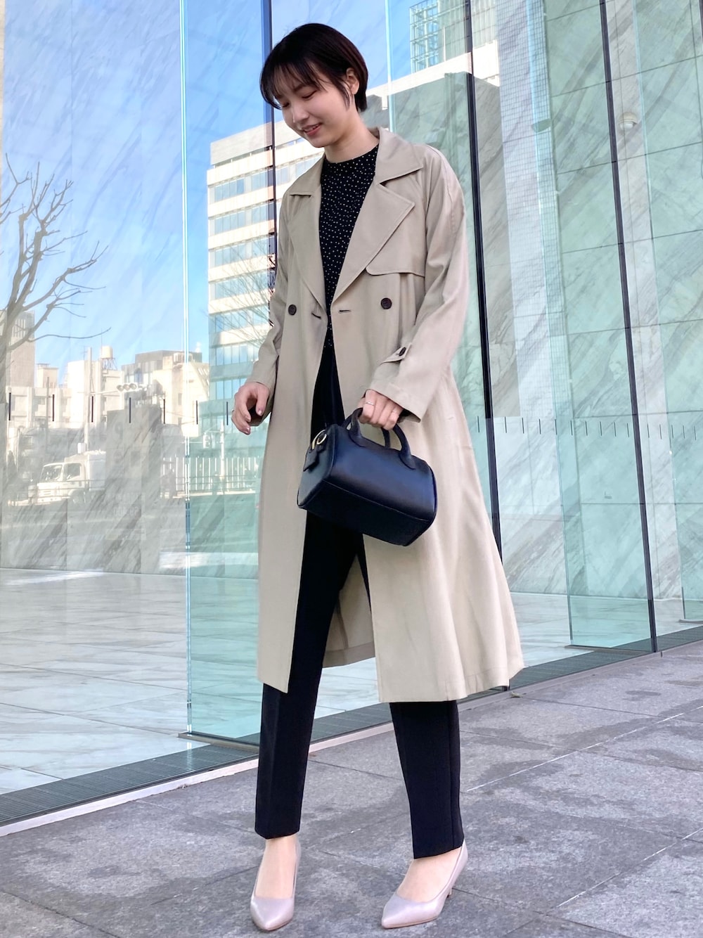 ベージュ系のトレンチコート、ブラック系のショルダーバッグ、ブラック系のその他パンツを着用したレディースの春コーディネートの1枚目の写真