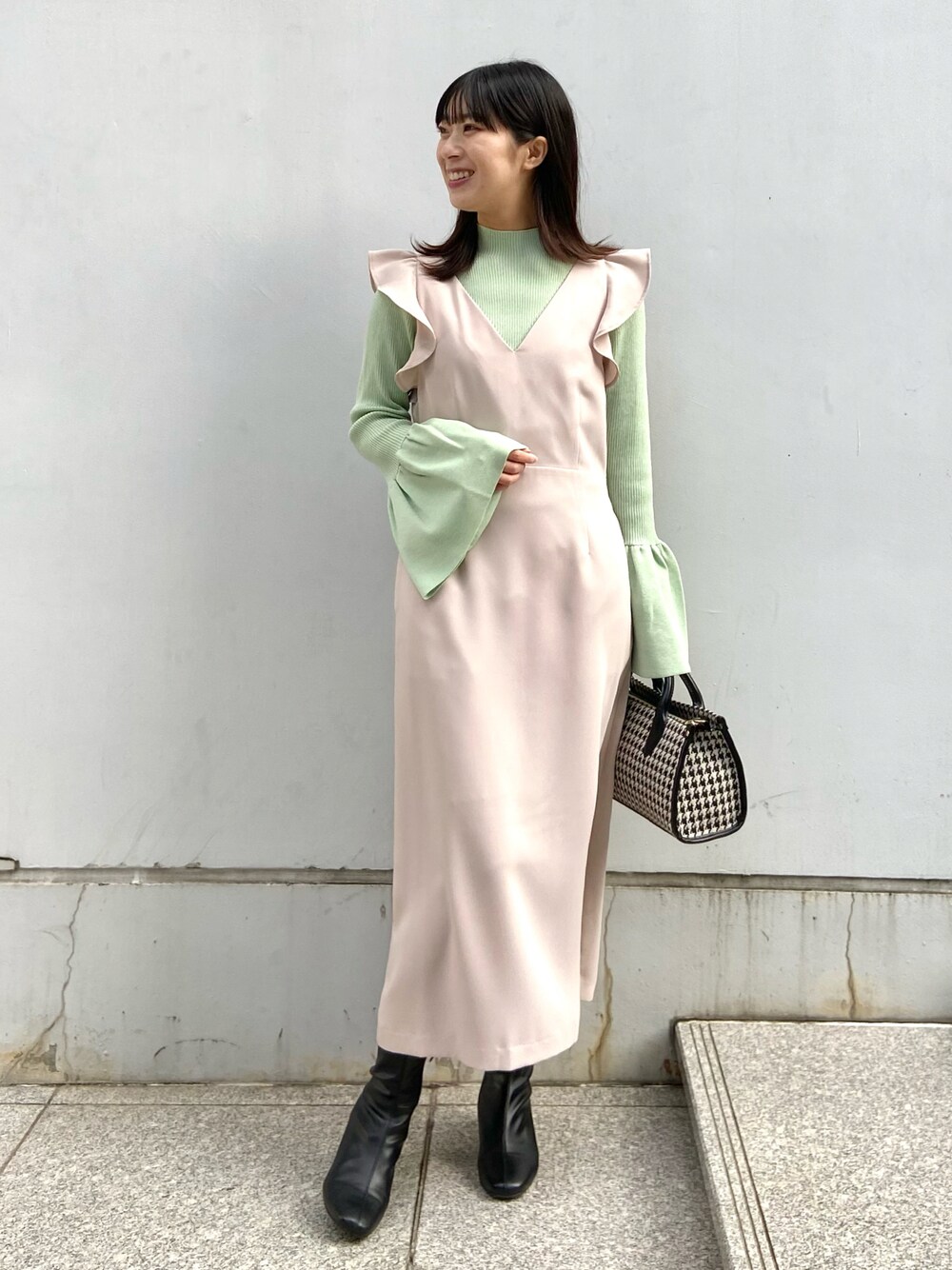 ベージュ系のスカート、グリーン系のニット/セーター、ブラック系のボストンバッグを着用したレディースの冬コーディネートの1枚目の写真