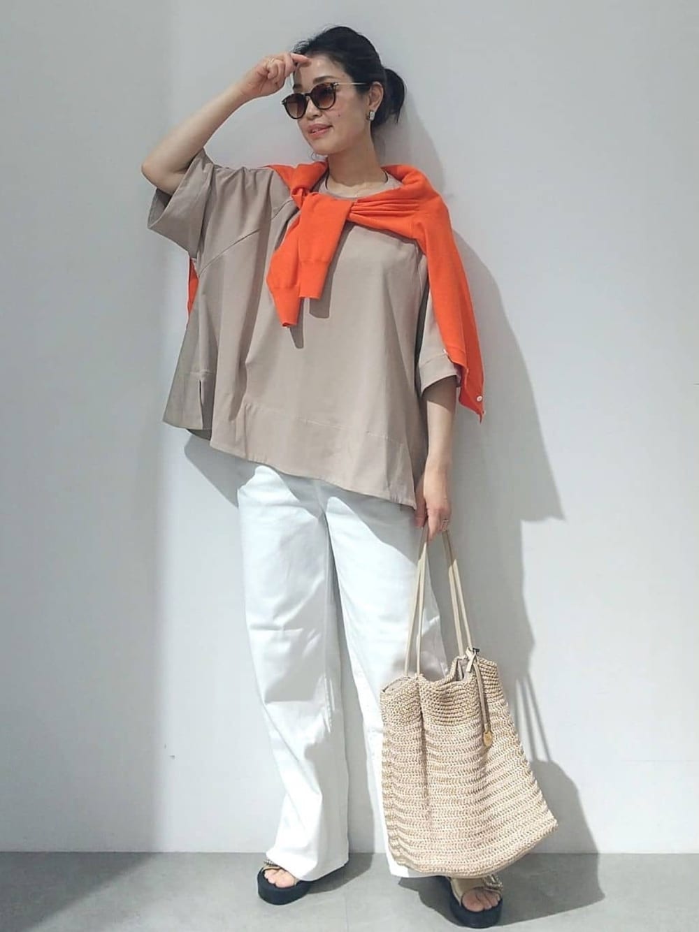 ベージュ系のTシャツ/カットソー、オレンジ系のカーディガン/ボレロ、ホワイト系のデニムパンツを着用したレディースの春コーディネートの1枚目の写真