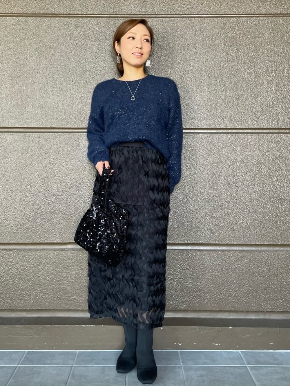 ブラック系のスカート、ブルー系のニット/セーター、ブラック系のブーツを着用したレディースの秋コーディネートの1枚目の写真