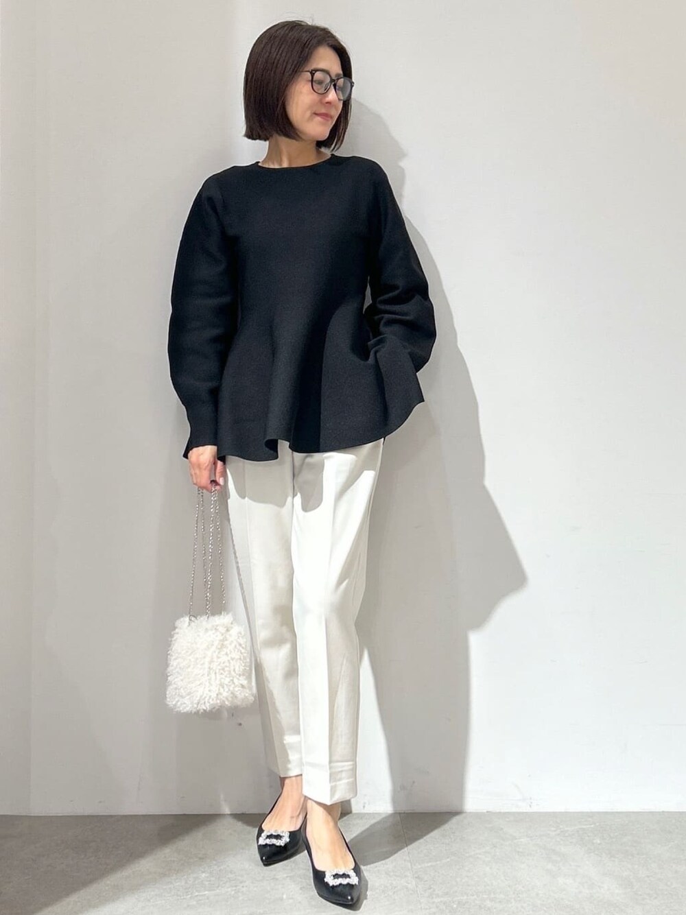 ブラック系のニット/セーター、ホワイト系のその他パンツ、ホワイト系のショルダーバッグを着用したレディースの冬コーディネートの1枚目の写真