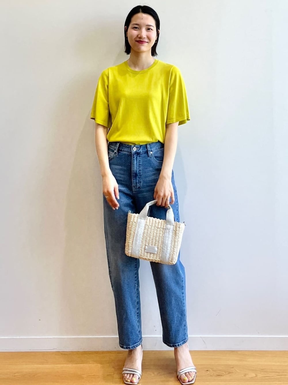 グリーン系のニット/セーター、ブルー系のデニムパンツ、シルバー系のショルダーバッグを着用したレディースの夏コーディネートの1枚目の写真