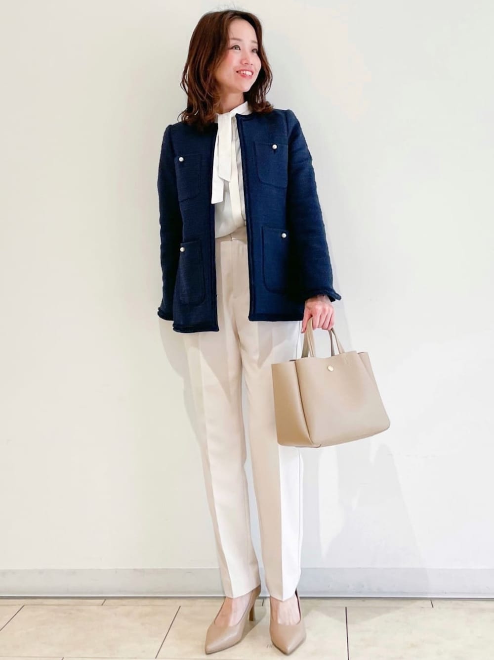 ブルー系のノーカラージャケット、ブラック系のパンプス、ベージュ系のその他パンツを着用したレディースの春コーディネートの1枚目の写真