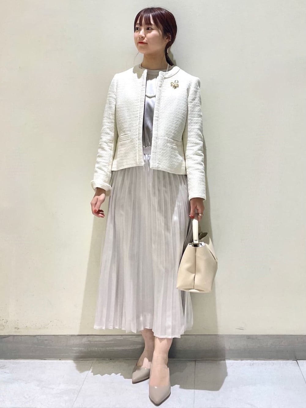 ホワイト系のノーカラージャケット、ベージュ系のワンピース、ベージュ系のショルダーバッグを着用したレディースの冬コーディネートの1枚目の写真