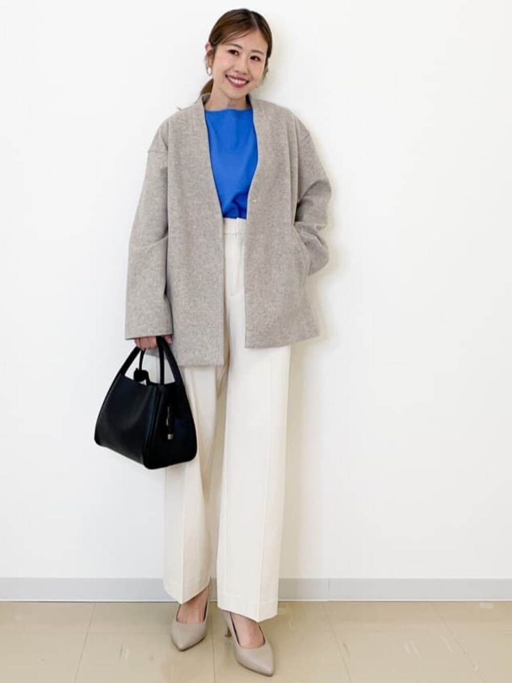 ベージュ系のノーカラーコート、ブルー系のニット/セーター、ホワイト系のその他パンツを着用したレディースの秋コーディネートの1枚目の写真