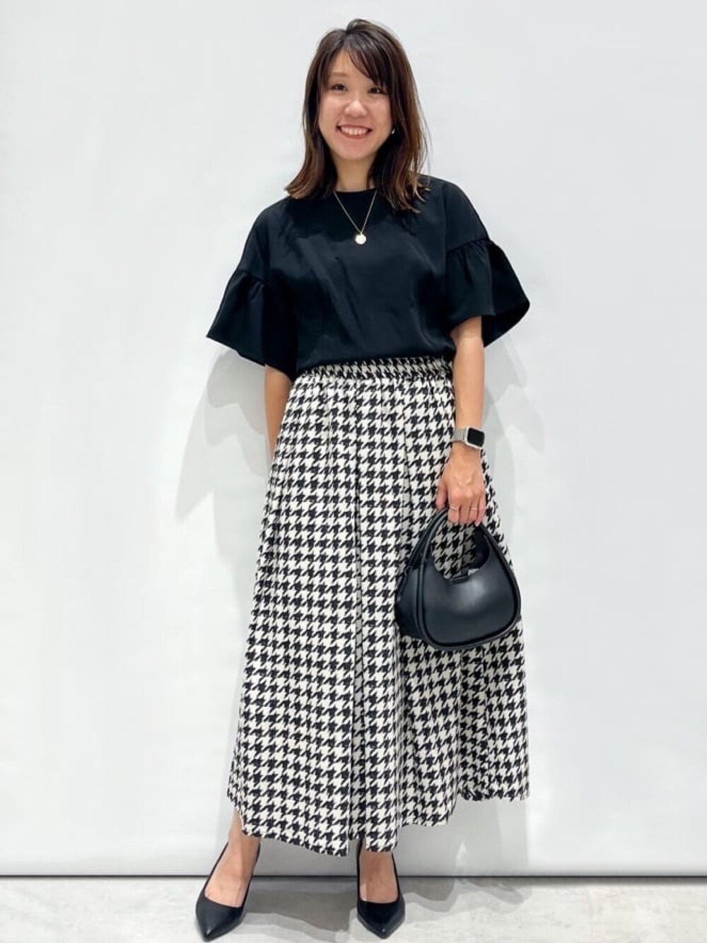 ブラック系のシャツ/ブラウス、ベージュ系のスカート、ブラック系のショルダーバッグを着用したレディースの秋コーディネートの1枚目の写真