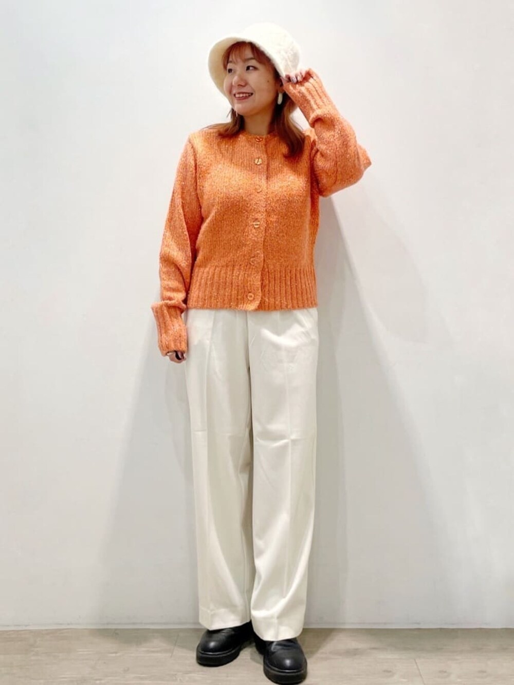 オレンジ系のカーディガン/ボレロ、ホワイト系のその他パンツ、ブラック系のブーツを着用したレディースの秋コーディネートの1枚目の写真