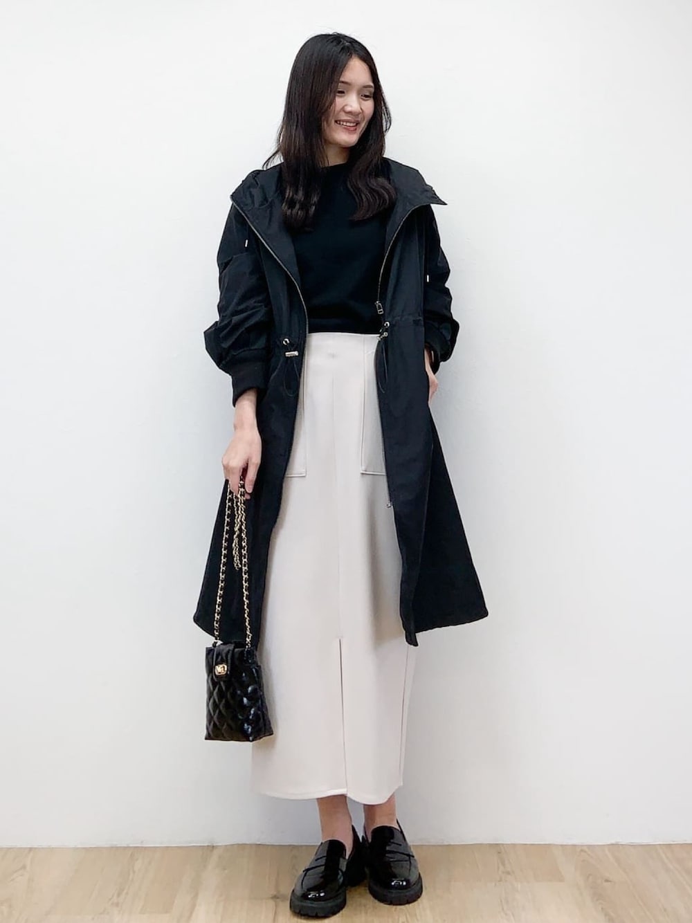 ブラック系のニット/セーター、ブラック系のその他アウター、ベージュ系のスカートを着用したレディースの春コーディネートの1枚目の写真