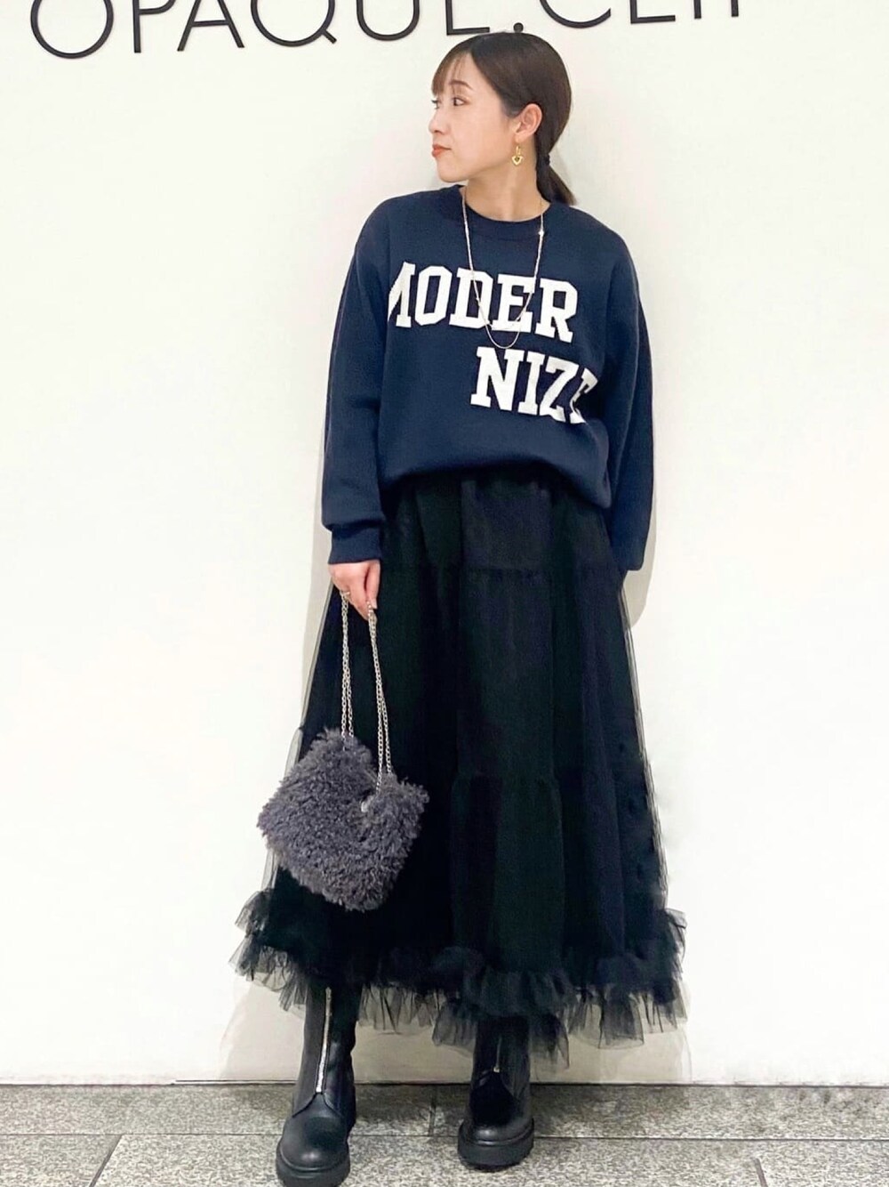 ブルー系のニット/セーター、ブラック系のスカート、グレー系のショルダーバッグを着用したレディースの冬コーディネートの1枚目の写真