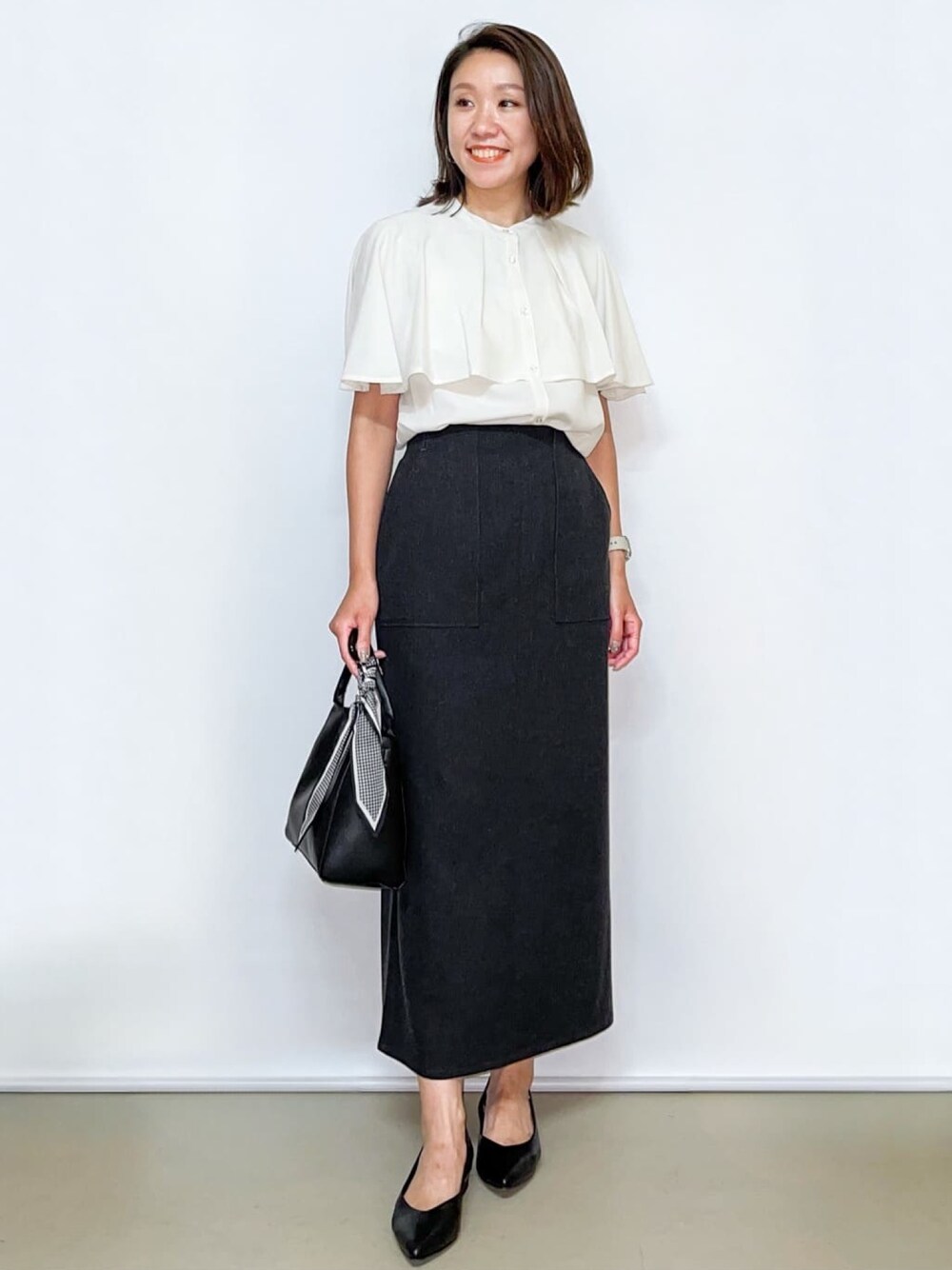 ホワイト系のシャツ/ブラウス、グレー系のスカート、ブラック系のトートバッグを着用したレディースの夏コーディネートの1枚目の写真