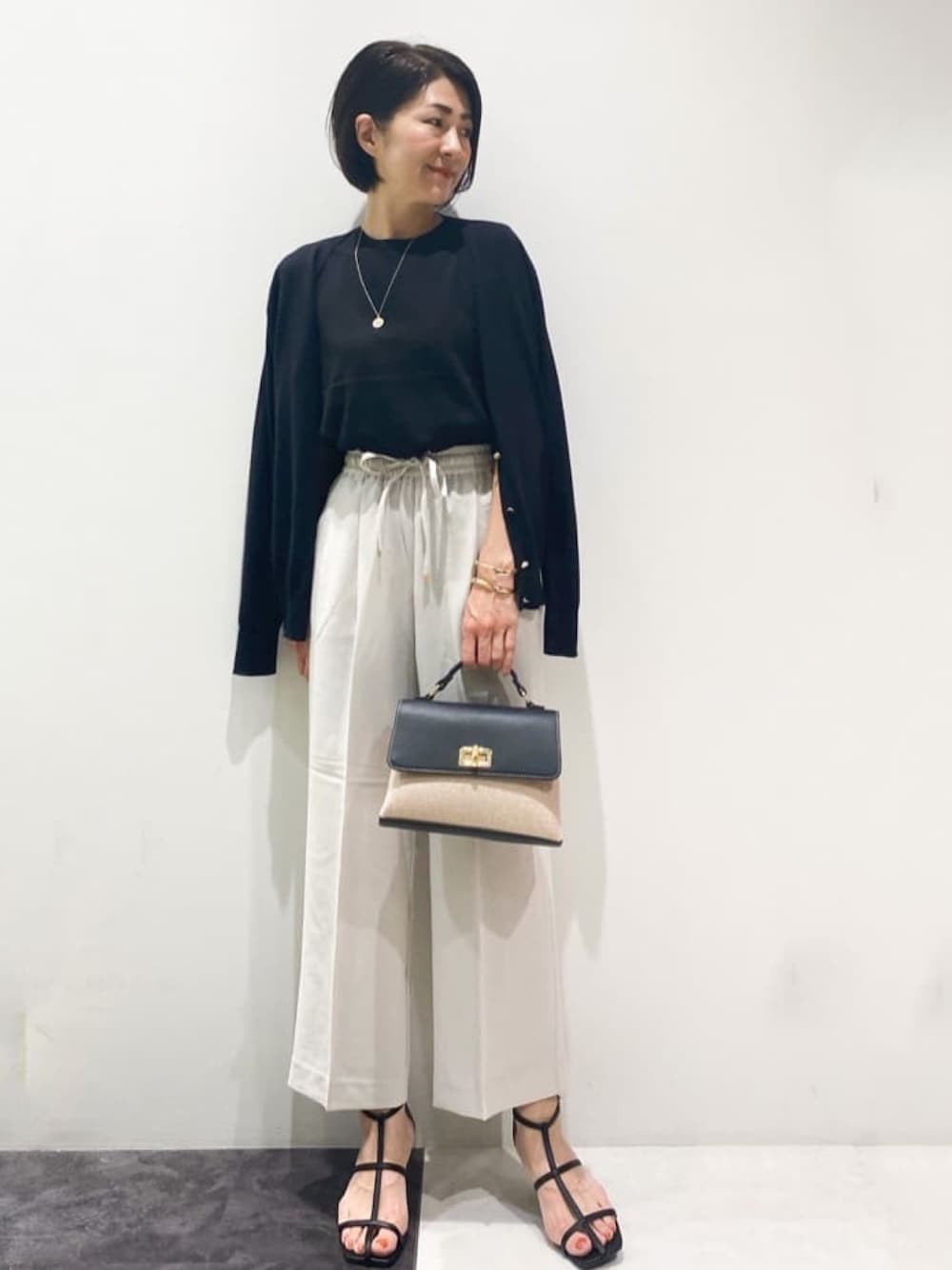 ブラック系のカーディガン/ボレロ、グレー系のその他パンツ、ブラック系のニット/セーターを着用したレディースの春コーディネートの1枚目の写真