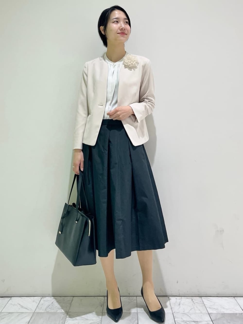 ベージュ系のノーカラージャケット、ブラック系のスカート、ブラック系のパンプスを着用したレディースの冬コーディネートの1枚目の写真