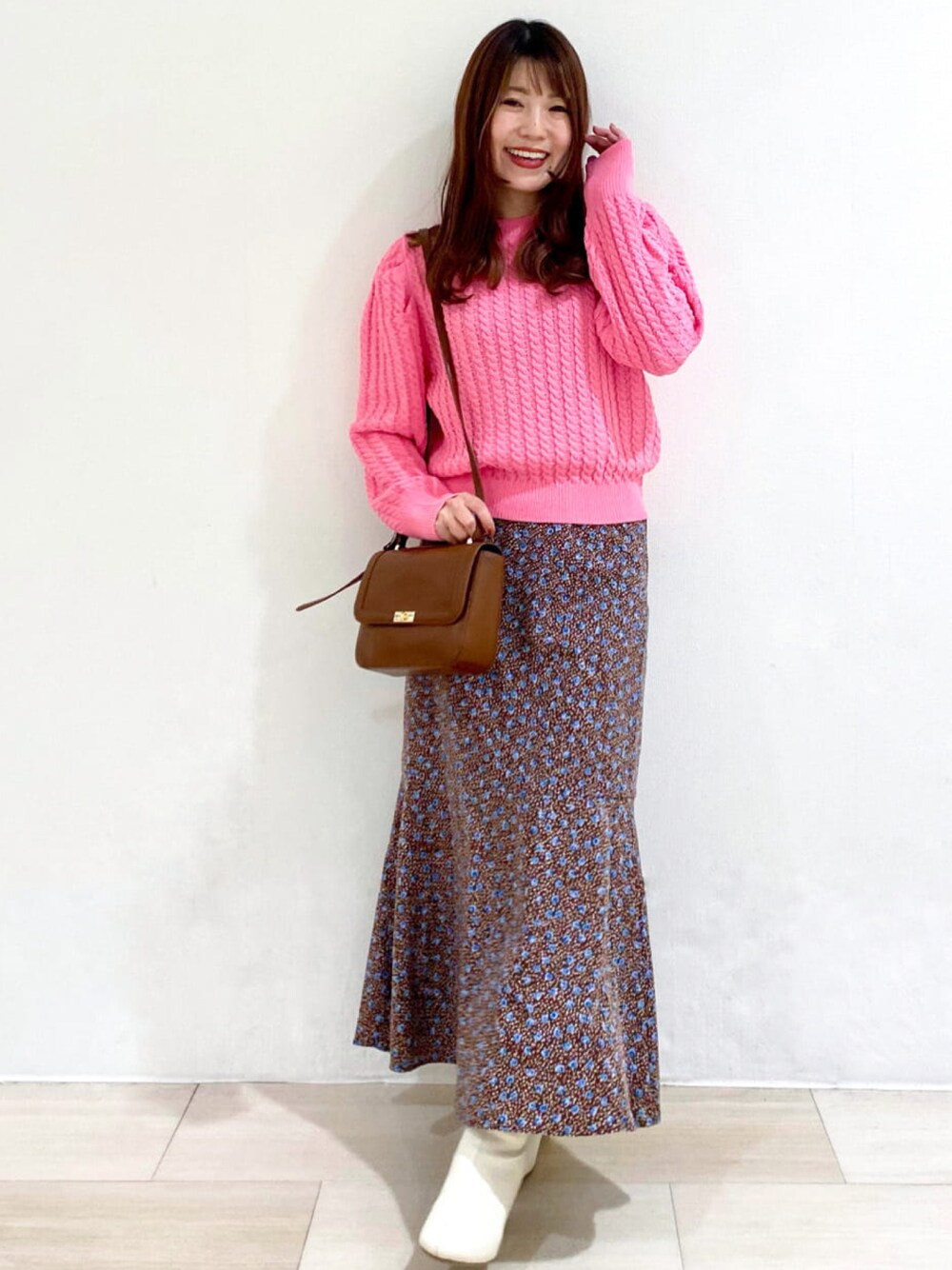 ピンク系のニット/セーター、ブラウン系のスカート、ホワイト系のブーツを着用したレディースの冬コーディネートの1枚目の写真