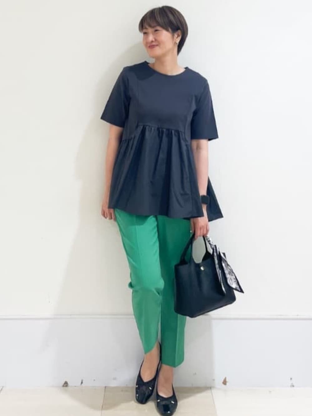 グレー系のTシャツ/カットソー、グリーン系のその他パンツ、ブラック系のトートバッグを着用したレディースの春コーディネートの1枚目の写真