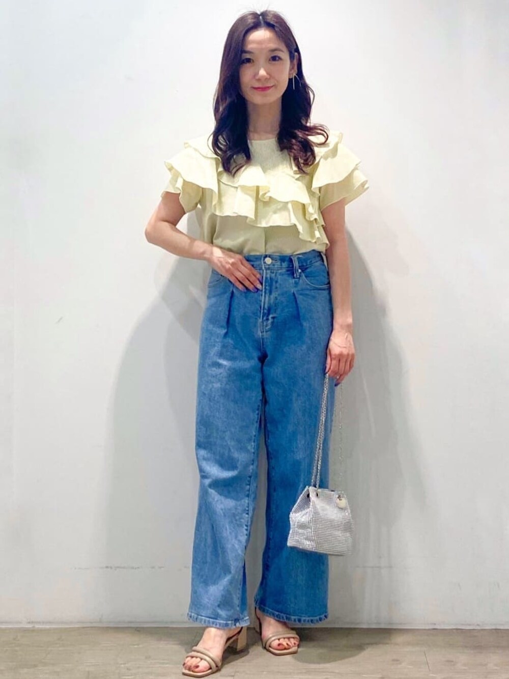 イエロー系のシャツ/ブラウス、ブルー系のデニムパンツ、ホワイト系のショルダーバッグを着用したレディースの春コーディネートの1枚目の写真