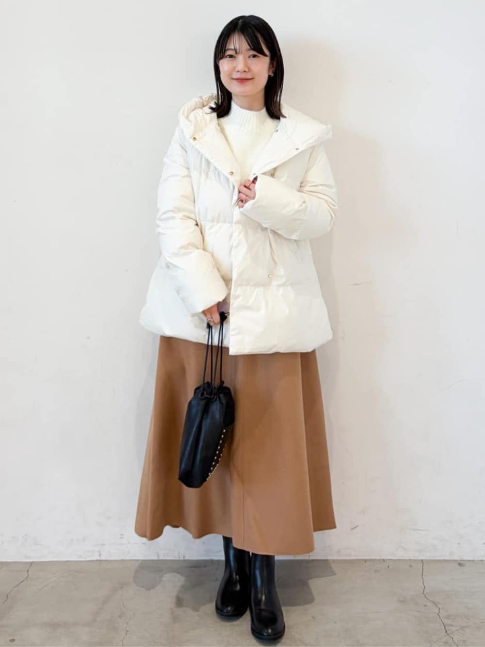 ホワイト系のダウンジャケット/コート、ホワイト系のニット/セーター、イエロー系のスカートを着用したレディースの冬コーディネートの1枚目の写真