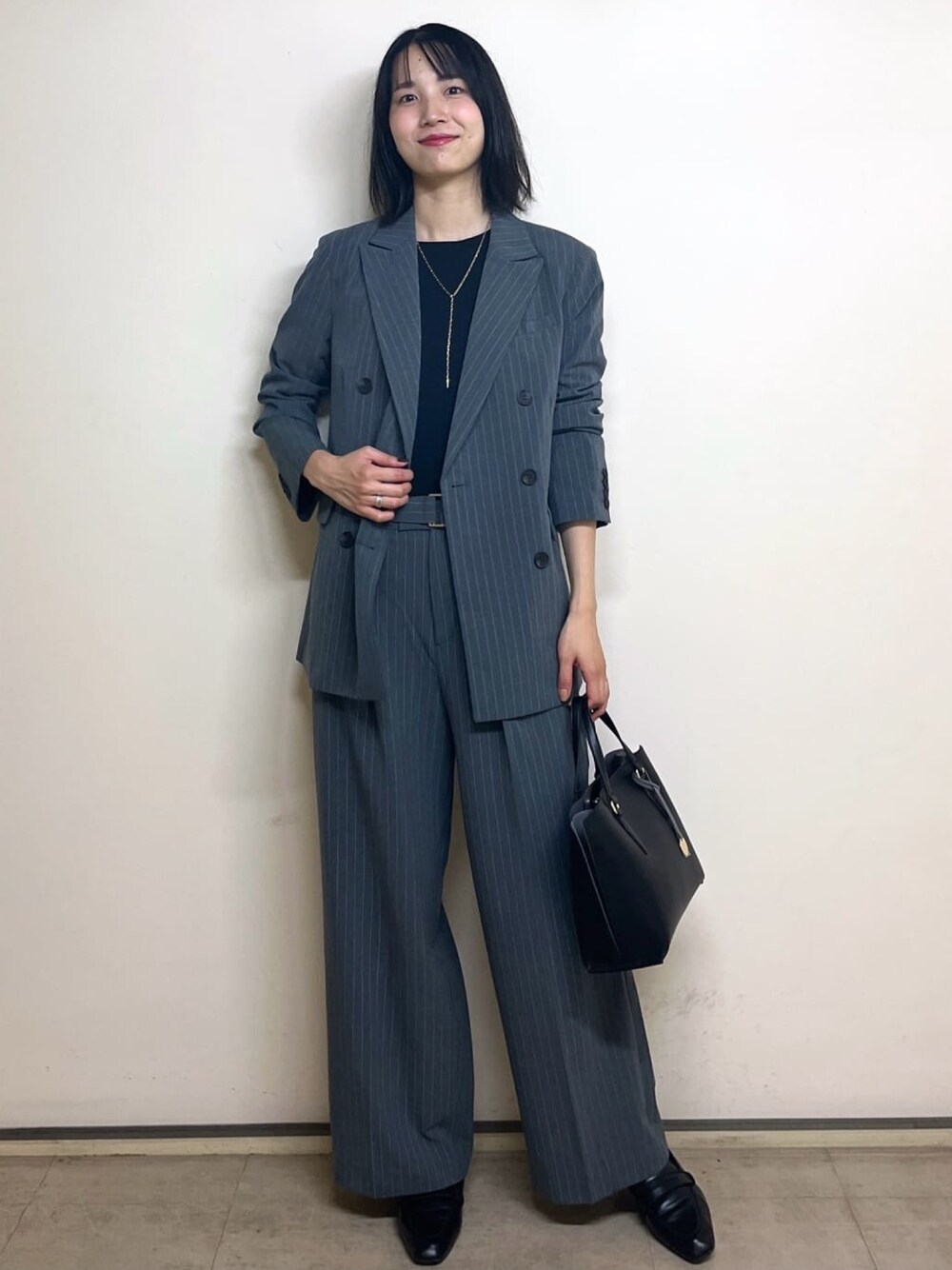 グレー系のテーラードジャケット、ブラック系のTシャツ/カットソー、ブラック系のトートバッグを着用したレディースの秋コーディネートの1枚目の写真