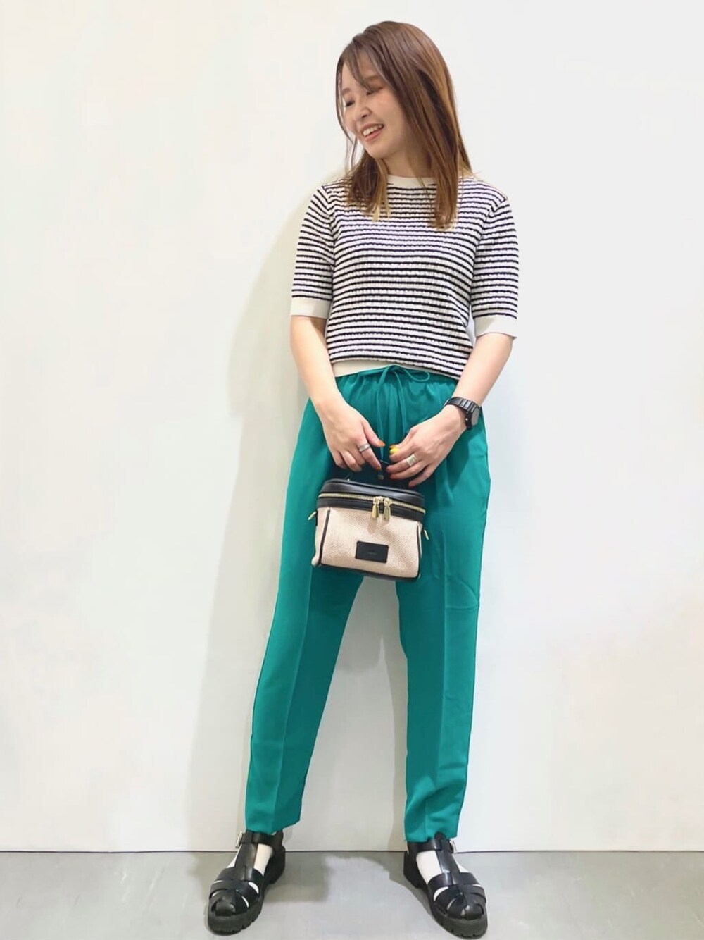 ホワイト系のニット/セーター、グリーン系のその他パンツ、ブラック系のショルダーバッグを着用したレディースの夏コーディネートの1枚目の写真