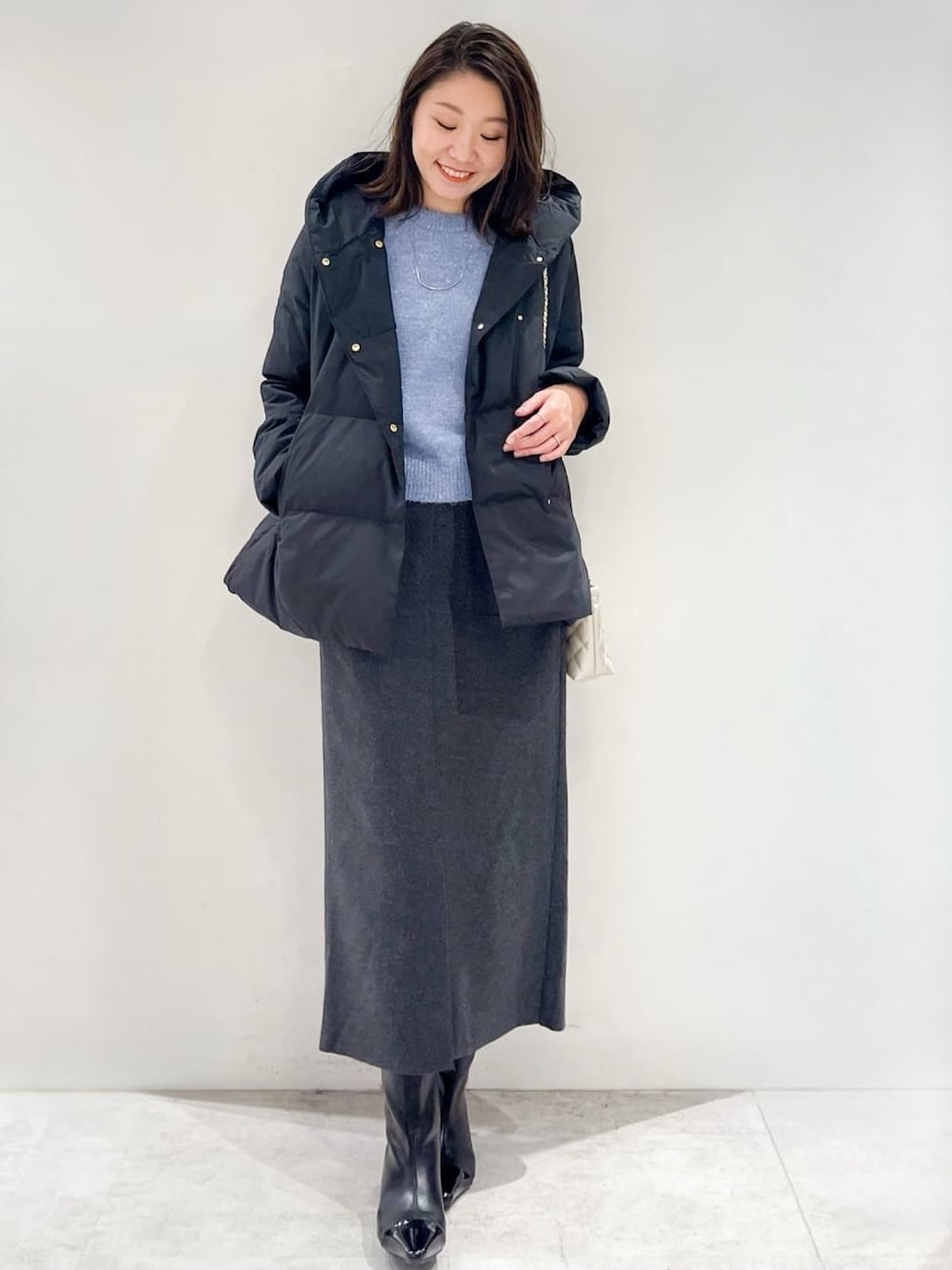 ブラック系のダウンジャケット/コート、グレー系のスカート、ブラック系のブーツを着用したレディースの秋コーディネートの1枚目の写真