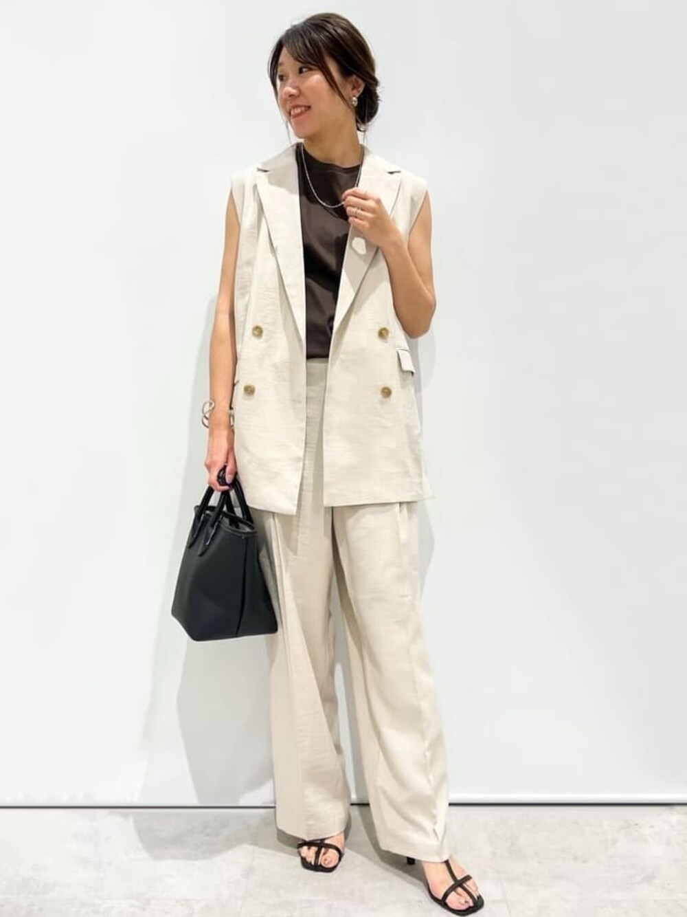 ベージュ系のその他パンツ、ブラック系のトートバッグ、ブラック系のサンダルを着用したレディースの夏コーディネートの1枚目の写真