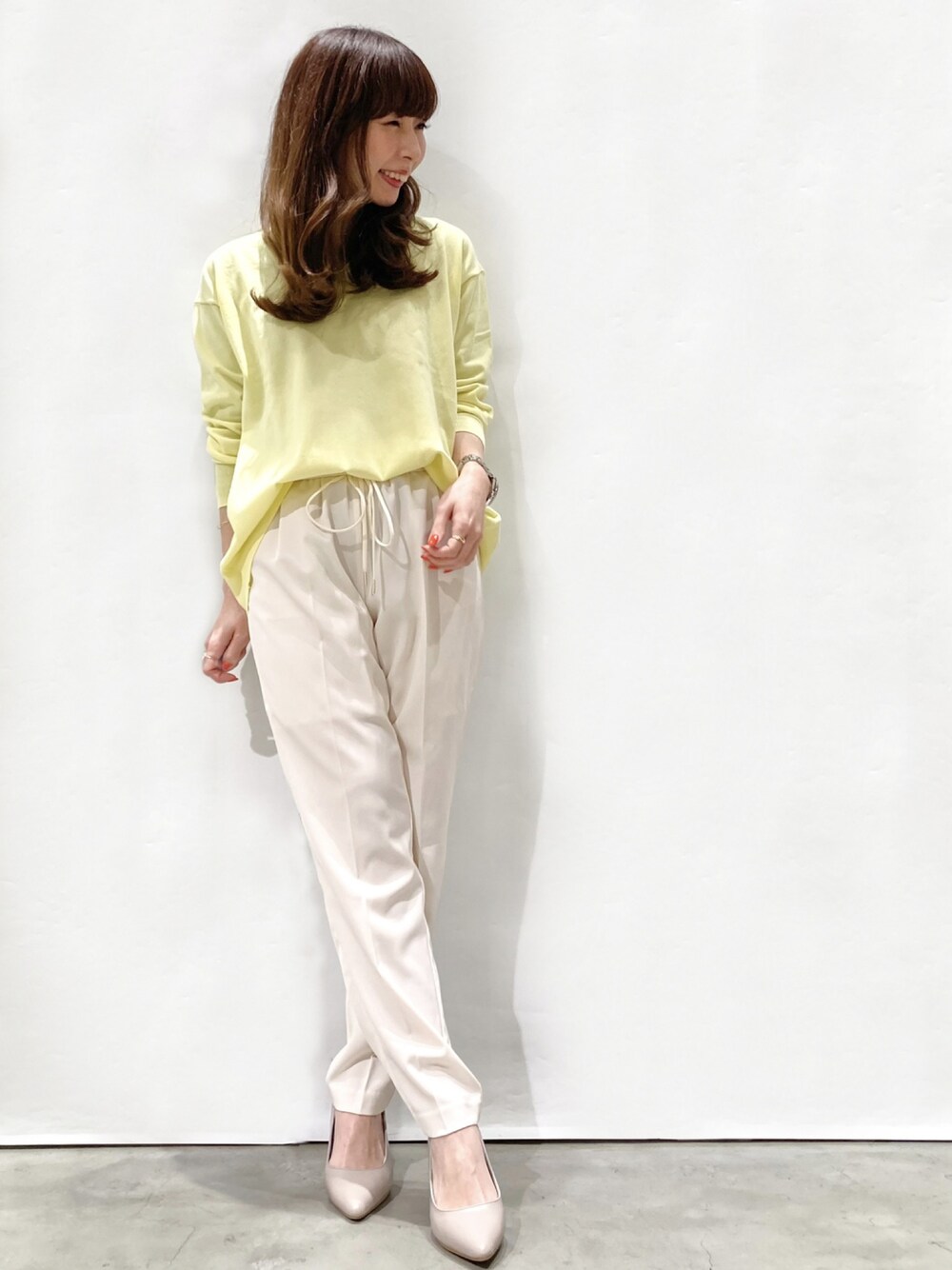 イエロー系のニット/セーター、ホワイト系のその他パンツ、グレー系のパンプスを着用したレディースの春コーディネートの1枚目の写真