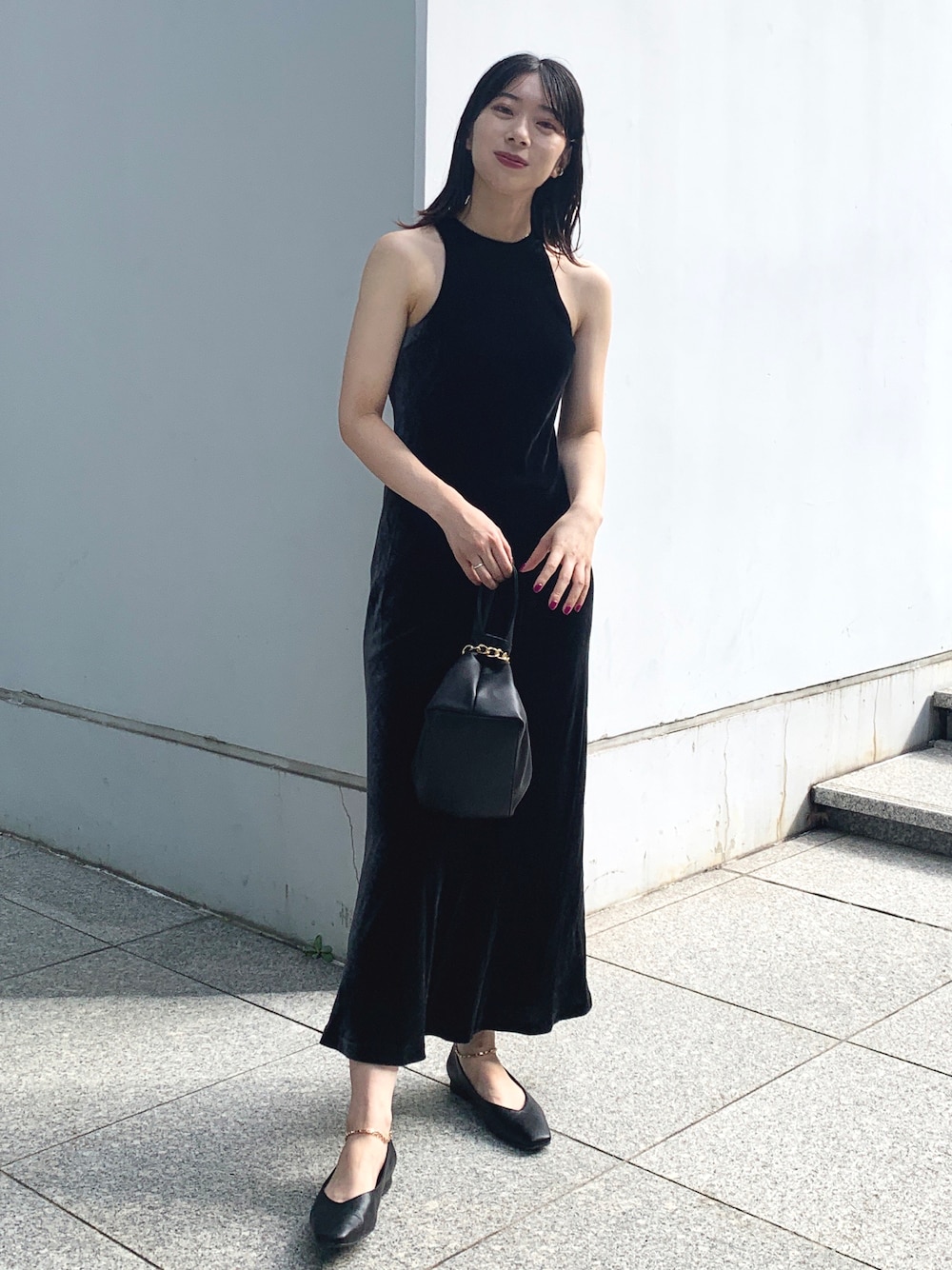 ブラック系のワンピース、ブラック系のハンドバッグ、ブラック系のパンプスを着用したレディースの夏コーディネートの1枚目の写真