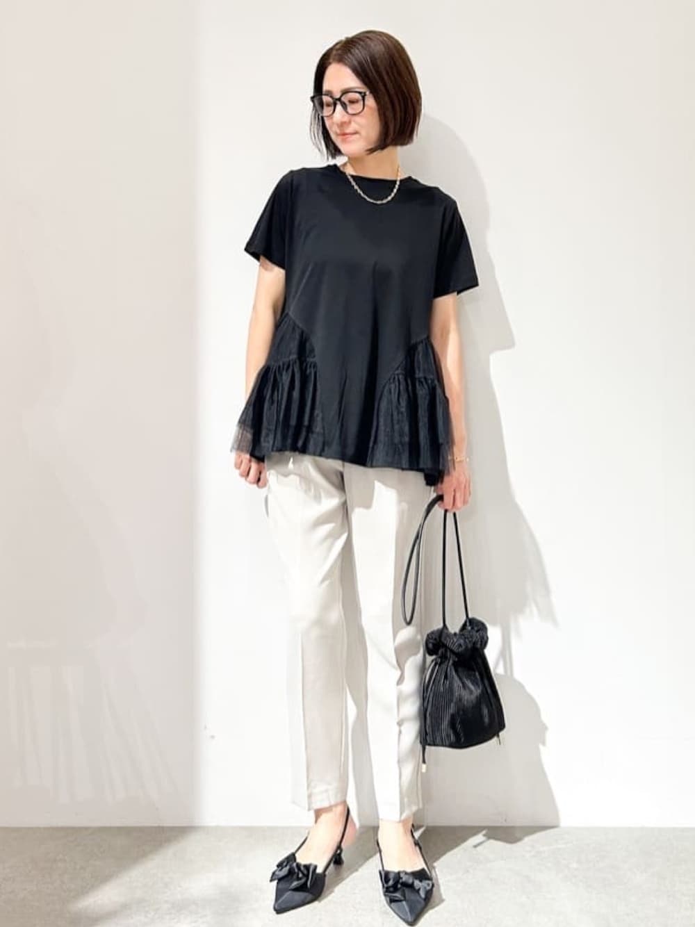 グレー系のその他パンツ、ブラック系のショルダーバッグ、ブラック系のパンプスを着用したレディースの春コーディネートの1枚目の写真